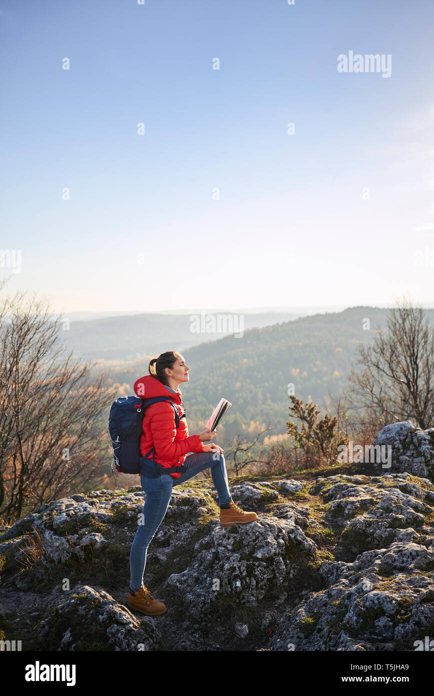 Woman on a hiking trip in the mountains holding map and enjoying beautiful view Stock Photo