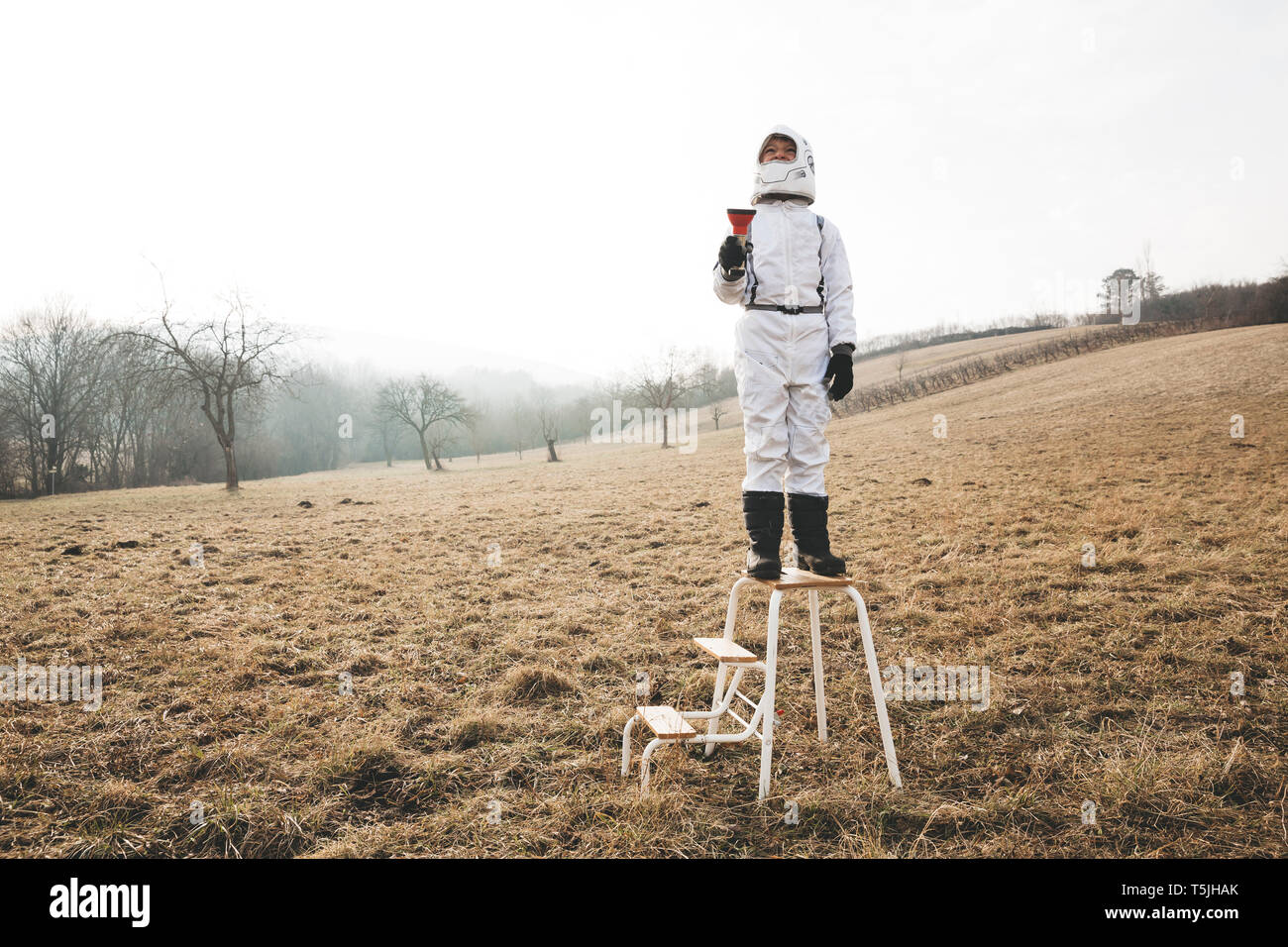 Boy wearing white space suit with flashlight on step Stock Photo