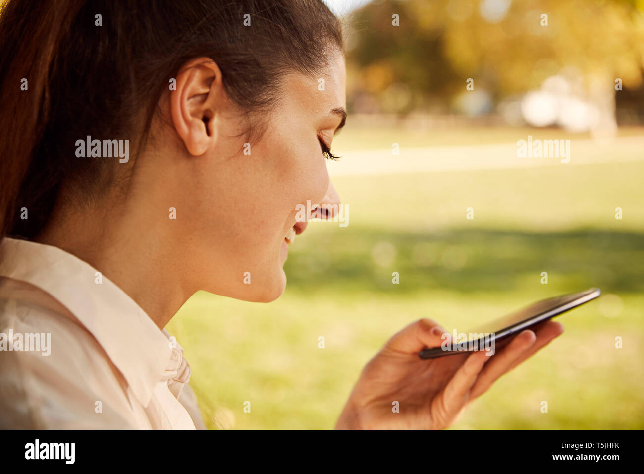 Happy young woman using smartphone in a park Stock Photo