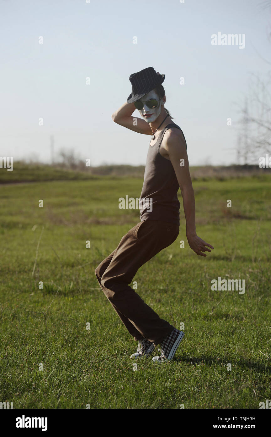 Portrait of young man with white face paint dancing on a meadow Stock Photo