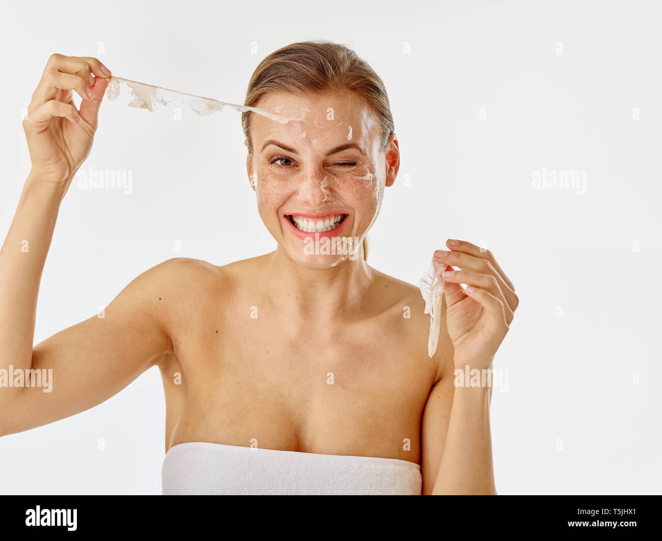 Young woman removing a facial mask Stock Photo