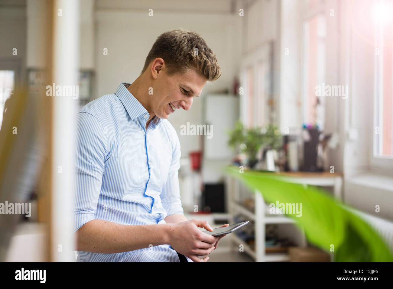 Smiling young businessman using tablet in office Stock Photo