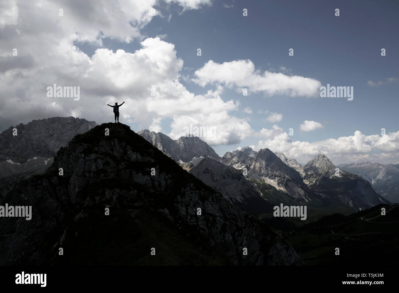 Austria, Tyrol, silhouette of man cheering on mountain peak Stock Photo