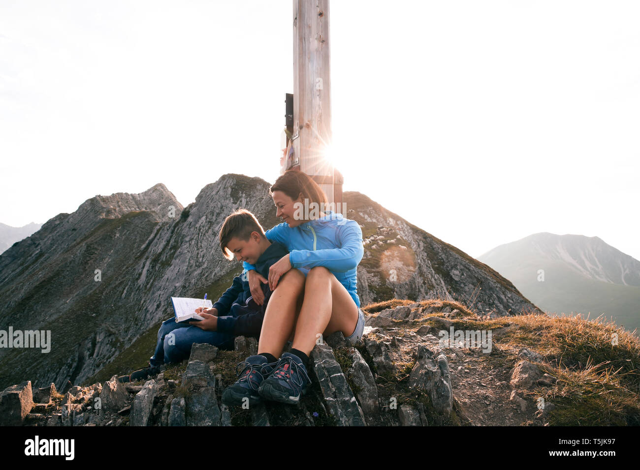 Austria, Tyrol, mother and son on a hiking trip with book at the summit Stock Photo