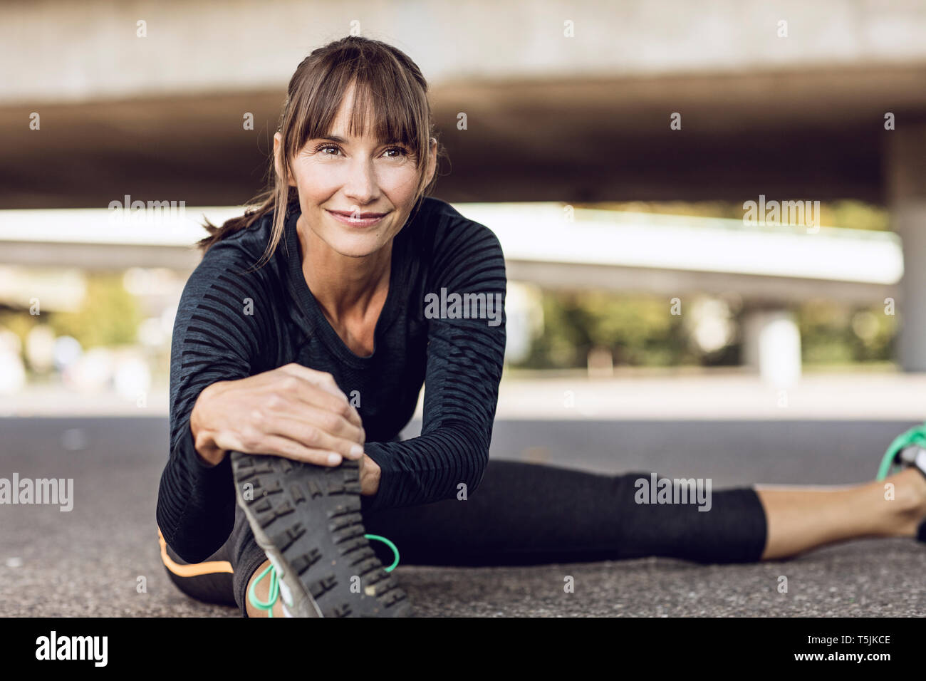 Sportive woman doing her fitness training outdoors, stretching Stock Photo