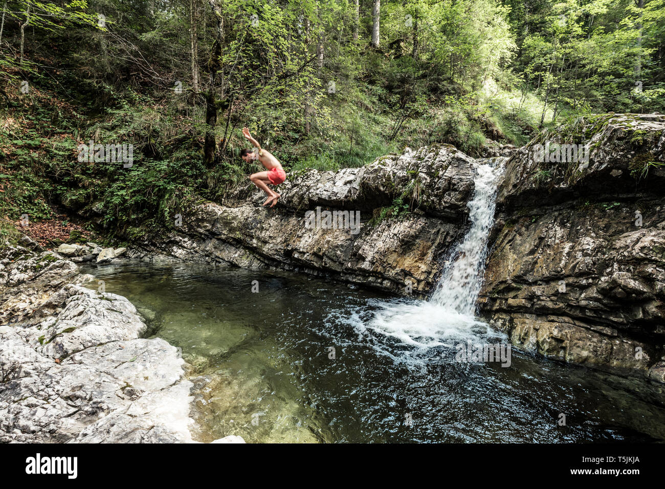 Germany, Upper Bavaria, Bavarian Prealps, lake Walchen, young man is jumping into a plunge pool Stock Photo