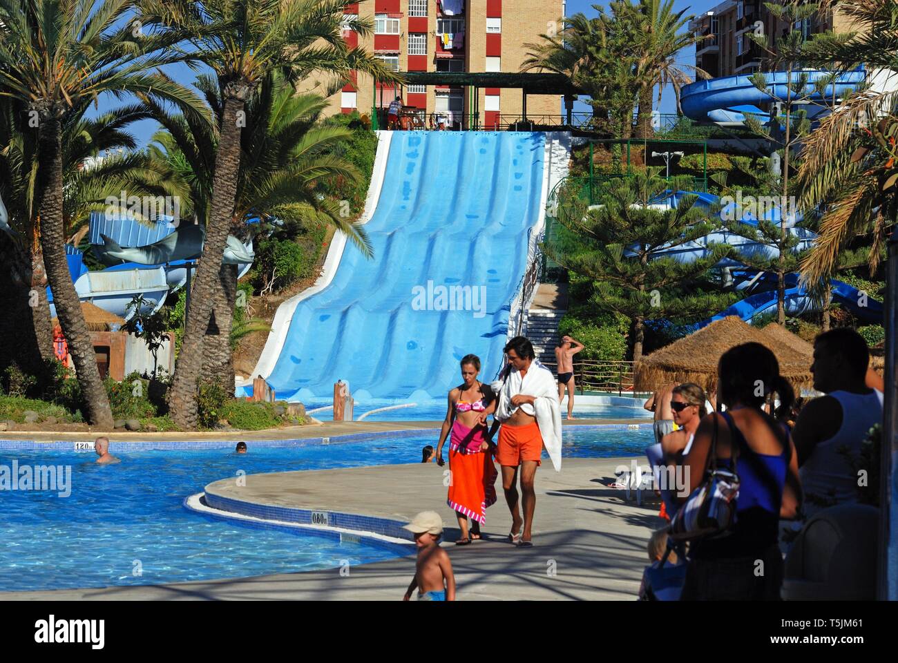 Water slide and pool in the water park with tourists enjoying the ...