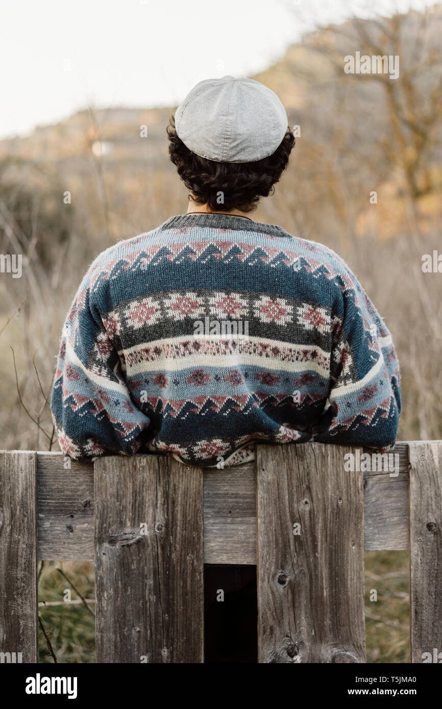 Young man leaning on fence, looking at view Stock Photo