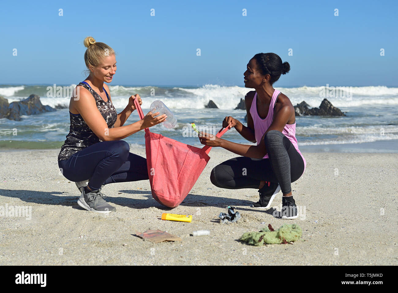Two women cleaning the beach from plastic waste Stock Photo - Alamy