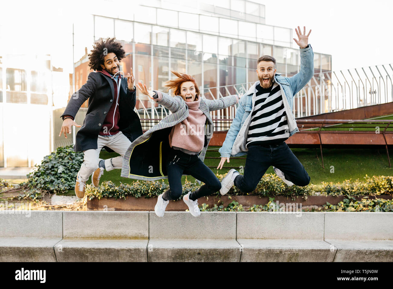 Three happy friends jumping in the city Stock Photo - Alamy