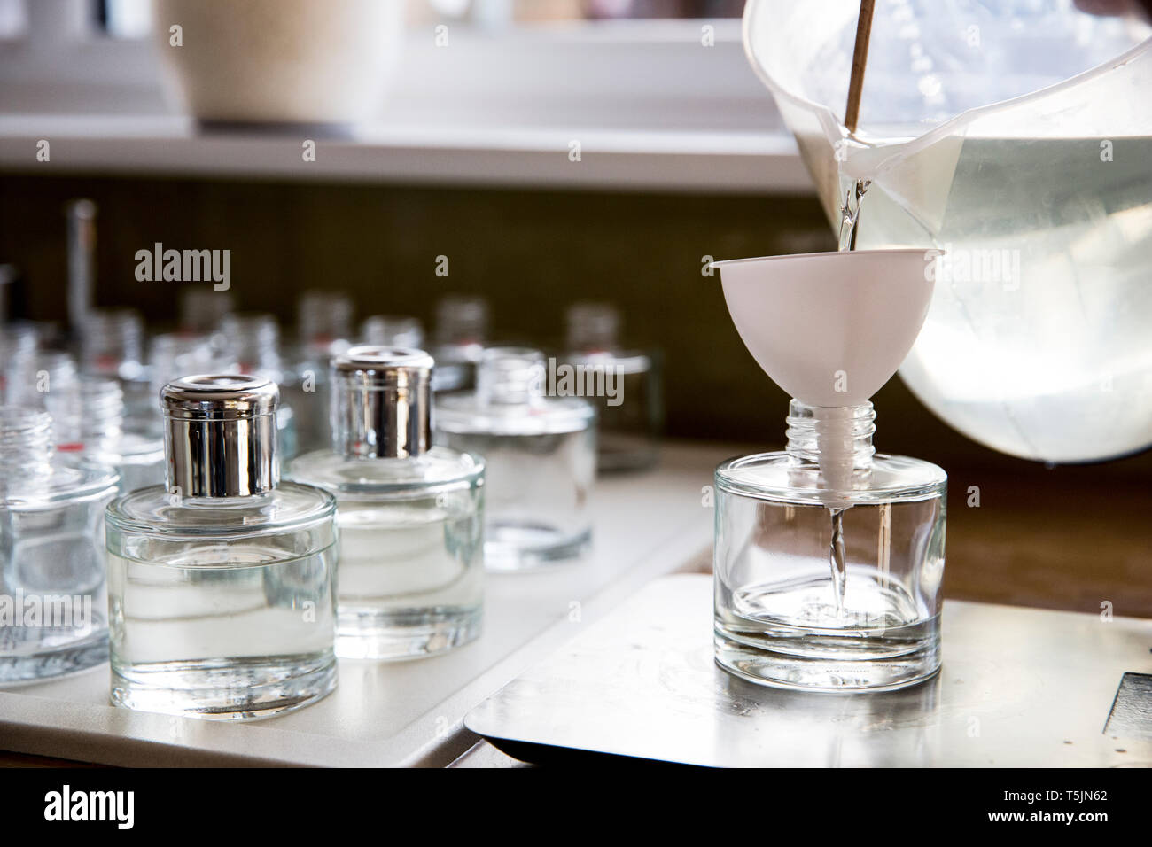 Close up of person pouring liquid for scent diffuser into glass bottle