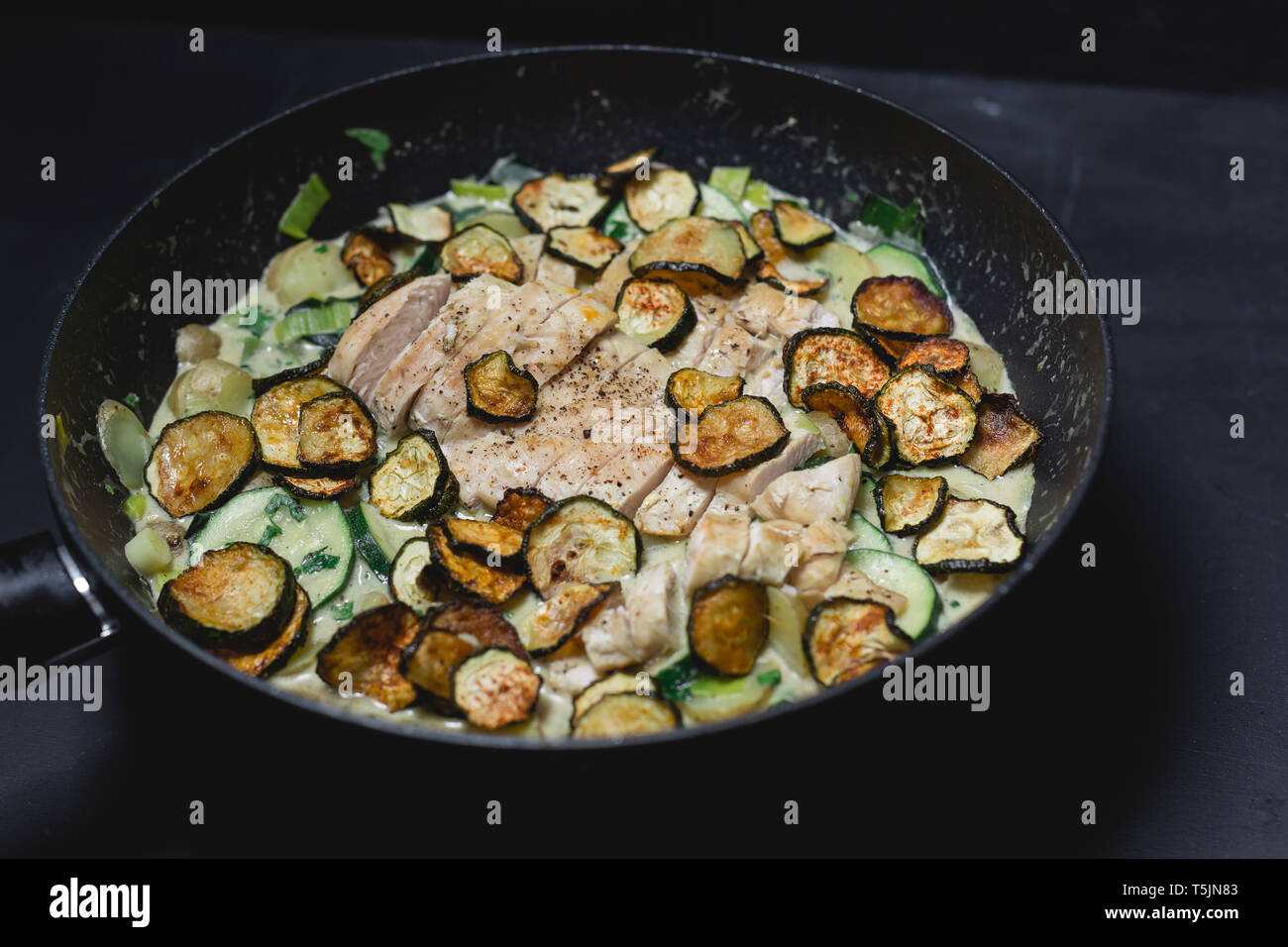 Chicken Zucchini Potato Stew with creme fraiche in a pan Stock Photo