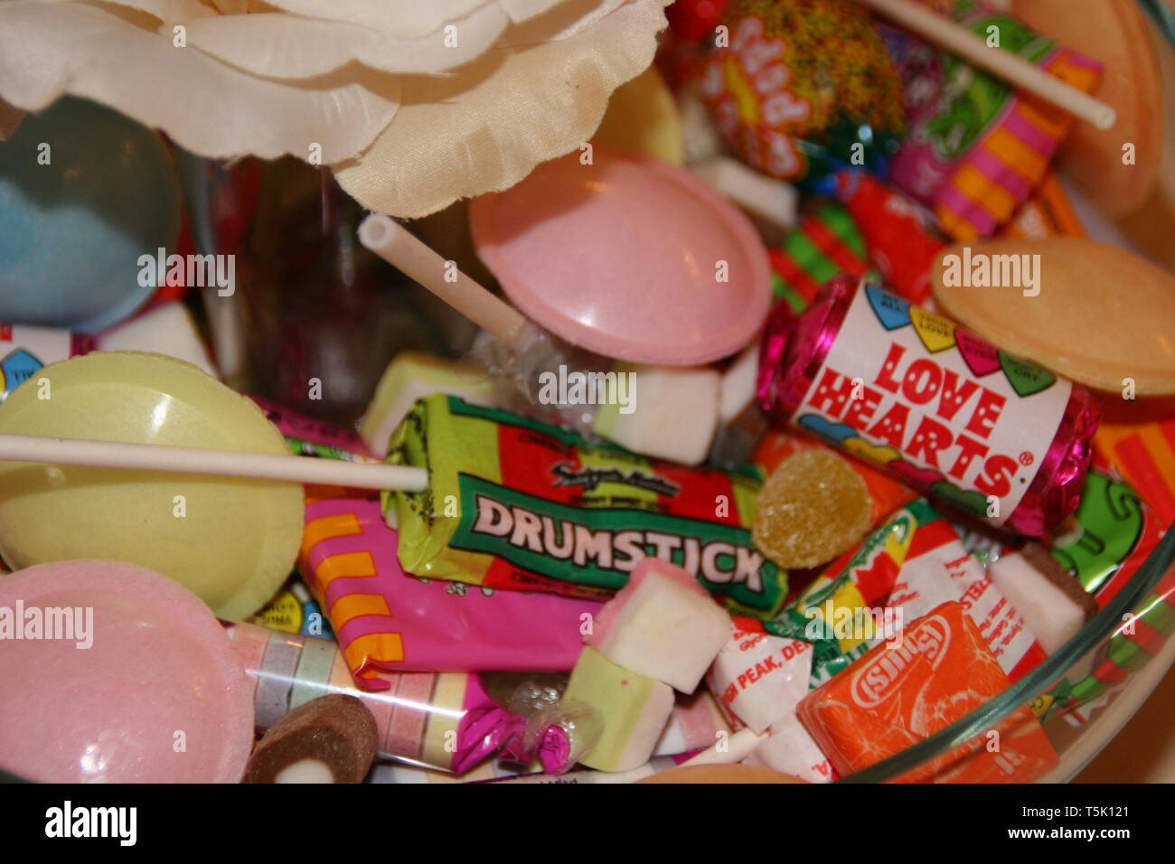 Retro sweets in a bowl, selection of love hearts, drumstick lolly and flying saucers in a glass bowl at a wedding reception Stock Photo