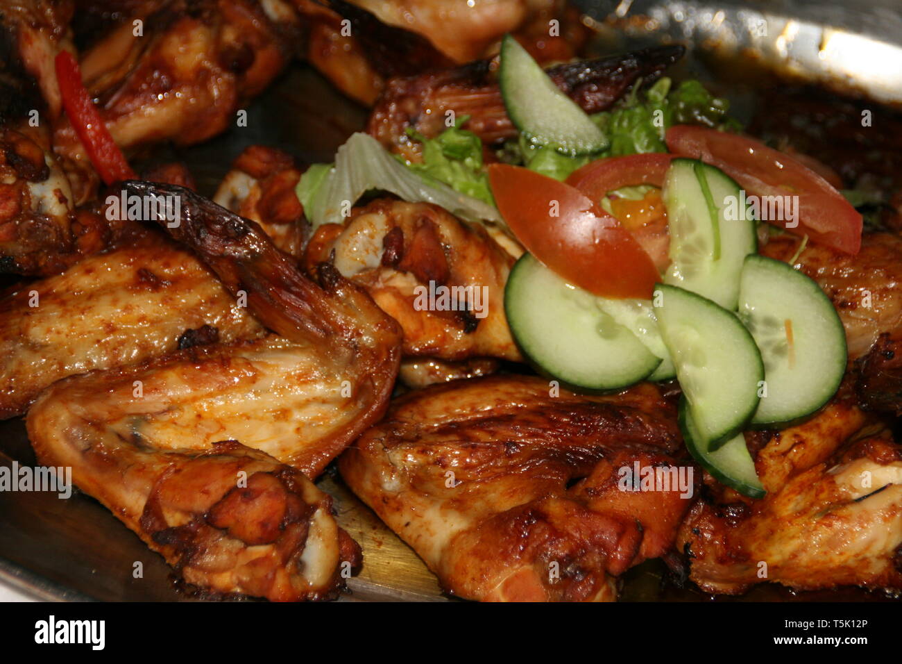 platter of chicken wings in bar- b - q sauce with salad at a party. Stock Photo