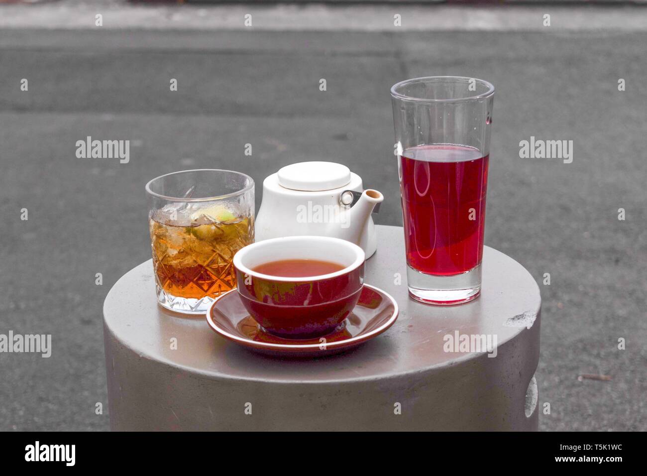 Tea served on a small round table in a selection of containers - cups and glasses and white teapot Stock Photo