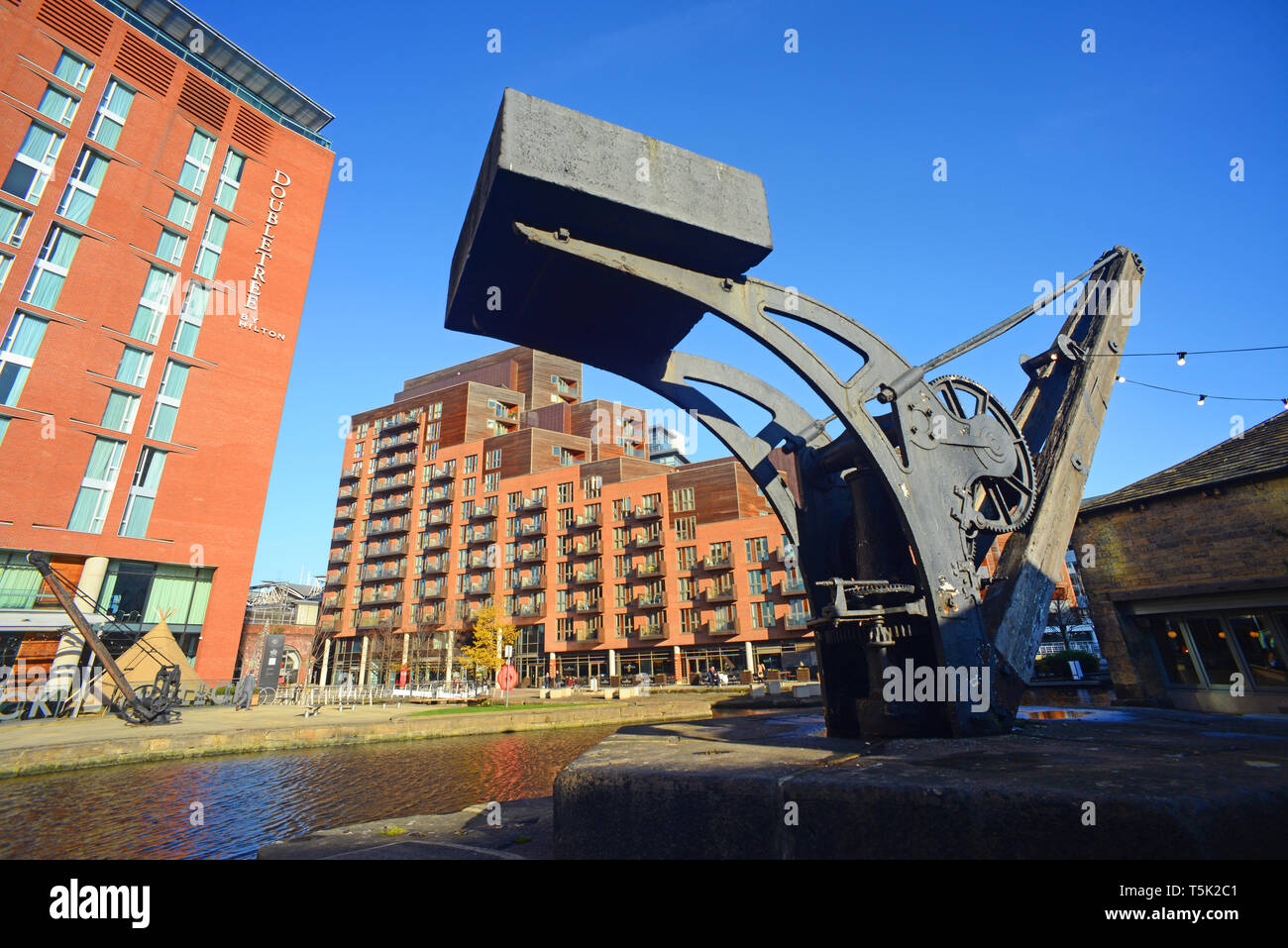 river aire  and old crane on quayside by shops and offices at clarence dock leeds yorkshire united kingdom Stock Photo