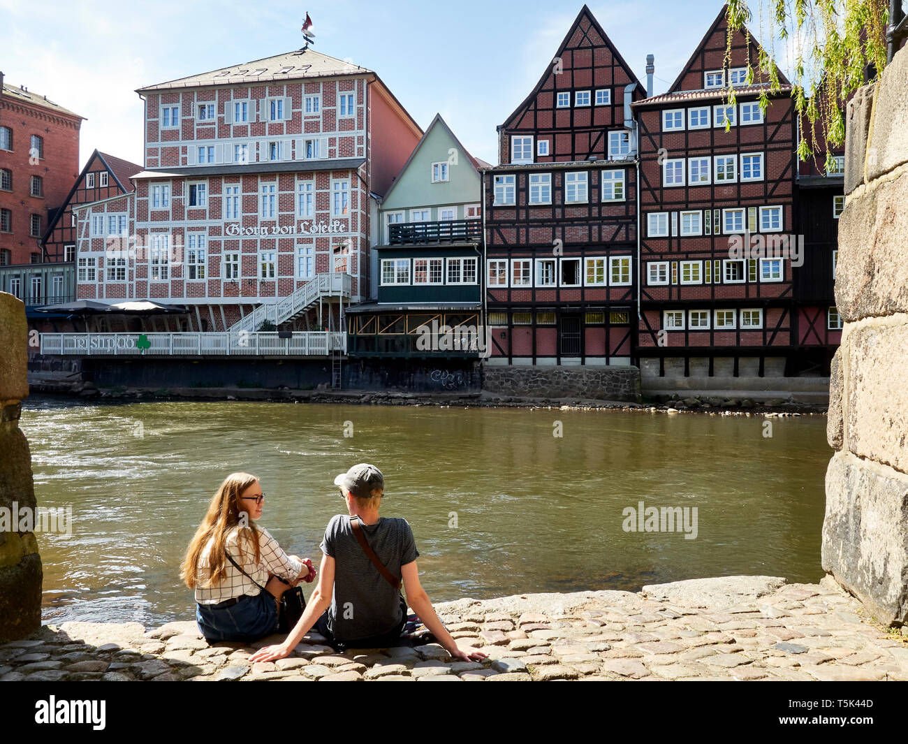 Young couple in front of timbered historic buildings, Lüneburg Harbour/port, Germany Stock Photo