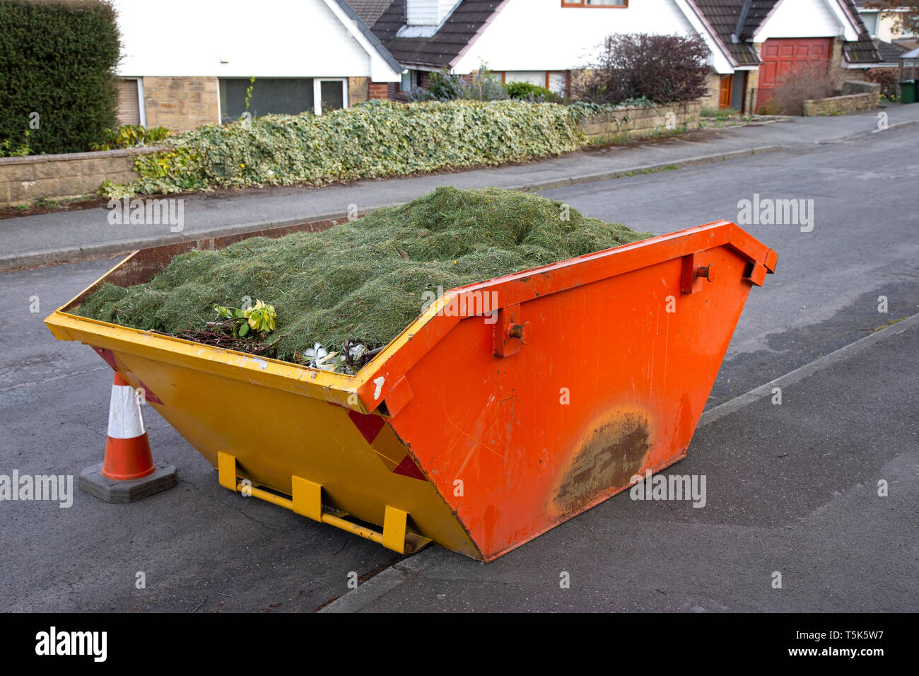 View of a skip on a public road filled with garden rubbish Stock Photo
