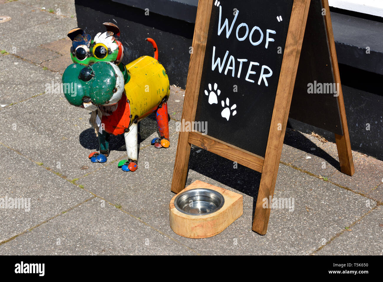 Dog watering dish with sign “Woof Water” outside shop on pavement Stock Photo
