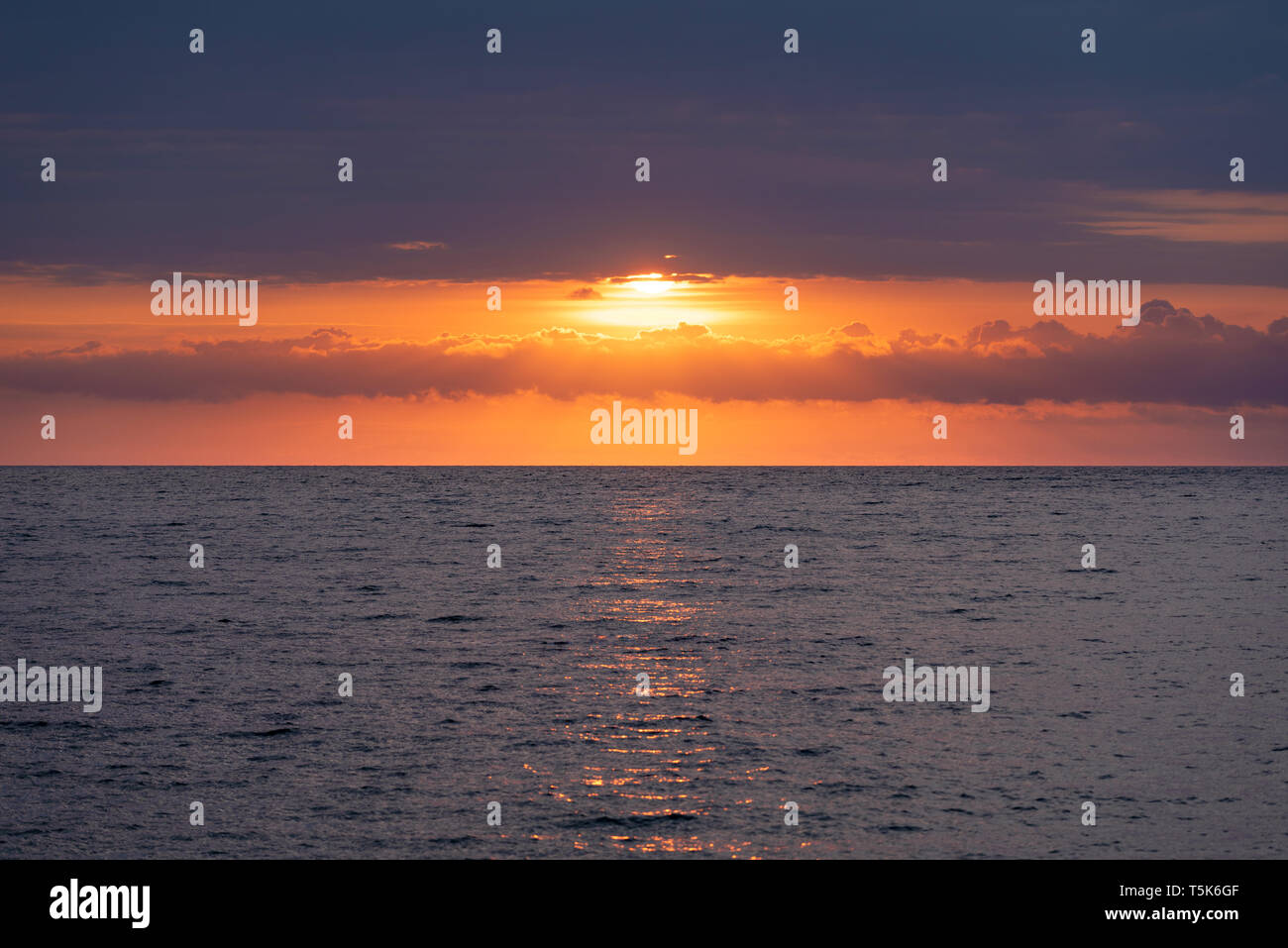 Seascape with a beautiful sunrise. The rising sun is hidden behind beautiful clouds Stock Photo