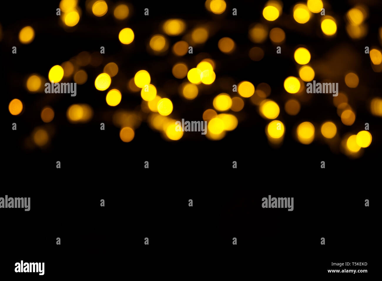 Abstract gold bokeh on black background. Defocused yellow lights