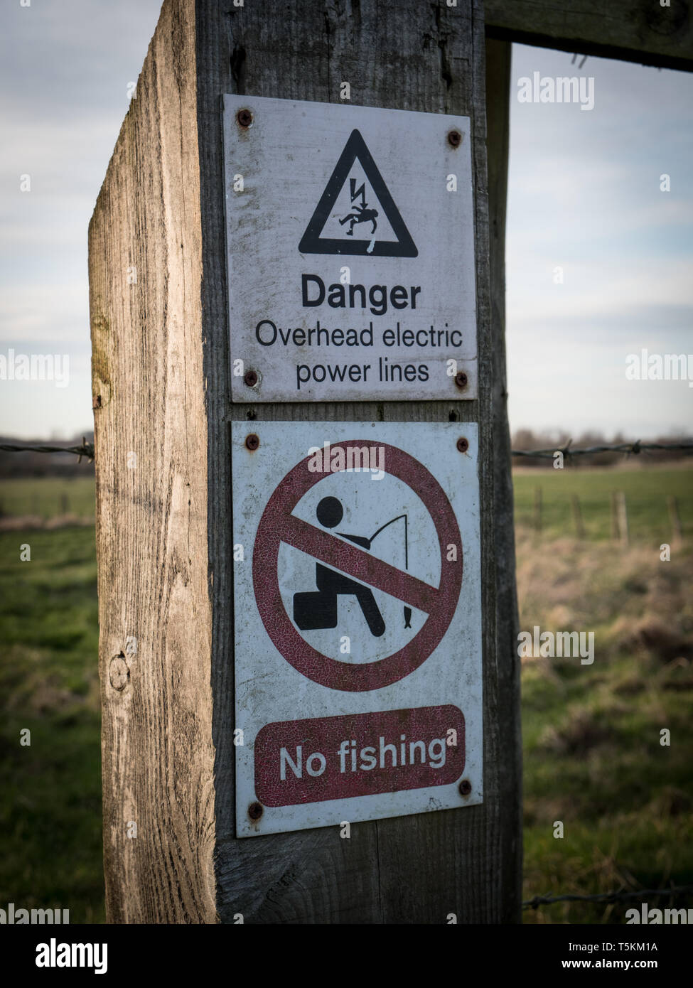 Safety warning signs relating to overhead power lines and fishing restrictions. England UK. Stock Photo