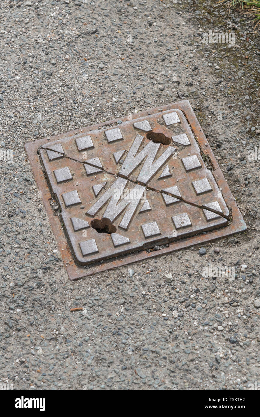 Water utility stopcock cover set in tarmac pavement. For water bills