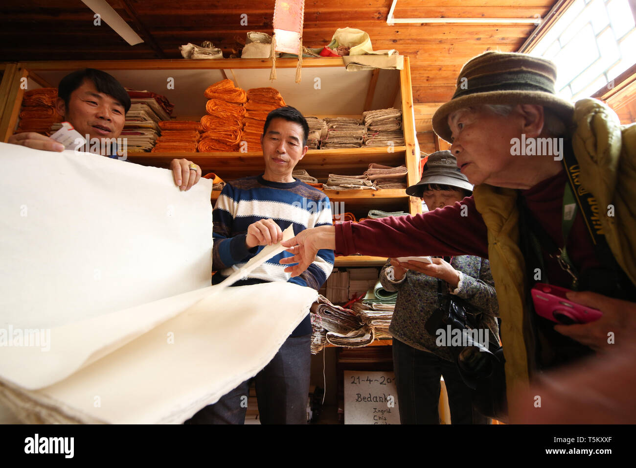(190425) -- DANZHAI, April 25, 2019 (Xinhua) -- Wang Xingwu (2nd L), a papermaker, introduces his paper product to Japanese tourists at a workshop in Shiqiao Village of Danzhai County, southwest China's Guizhou Province, April 24, 2019. Wang Xingwu, 53, a national intangible cultural heritage inheritor in papermaking, learned the papermaking technique from his family as a child. Besides exerting the old papermaking technique to its full potential, Wang keeps raising product quality and improving the making procedure. With the involvement of plants in the papermaking process, he has created mor Stock Photo