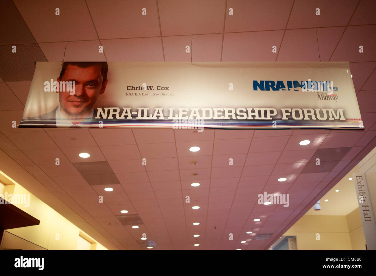 A photograph of NRA-ILA Executive Director Chris W. Cox is emblazoned on a banner over a hallway at the Indiana Convention Center. Vendors prepare booths in the exhibition hall before the National Rifle Association (NRA) convention at the Indiana Convention Center in downtown Indianapolis. Stock Photo