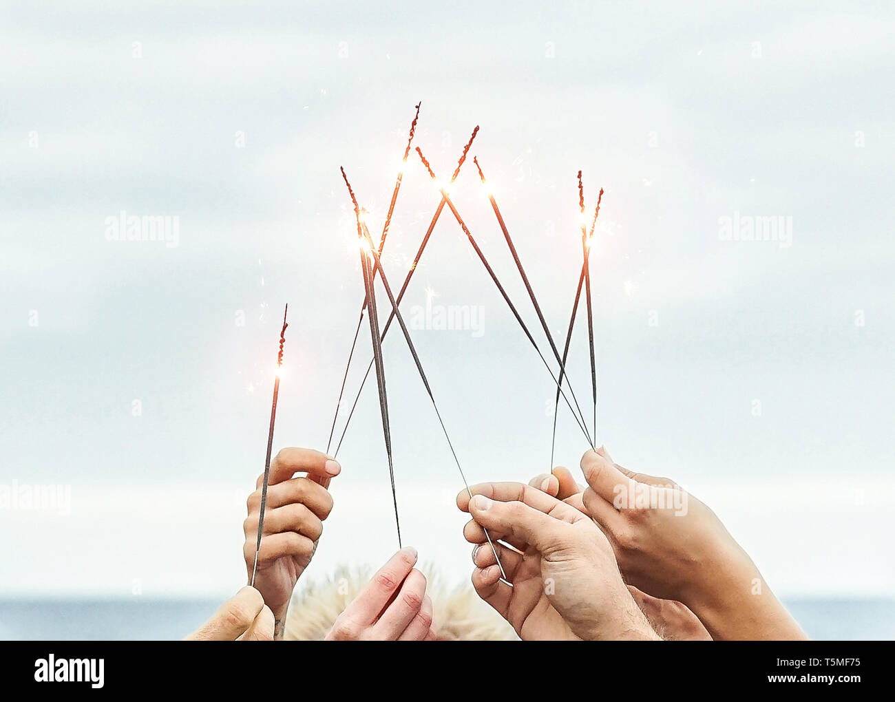 Close up hands of group of happy friends having fun celebrating with sparklers fireworks outdoor - Youth, celebrate, party lifestyle concept Stock Photo