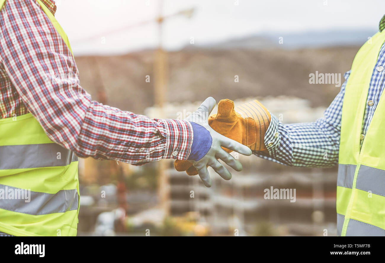 Close up builders hands making a deal - Workers on construction site reaching an agreement - Building, dealing, enginner industrial concept Stock Photo