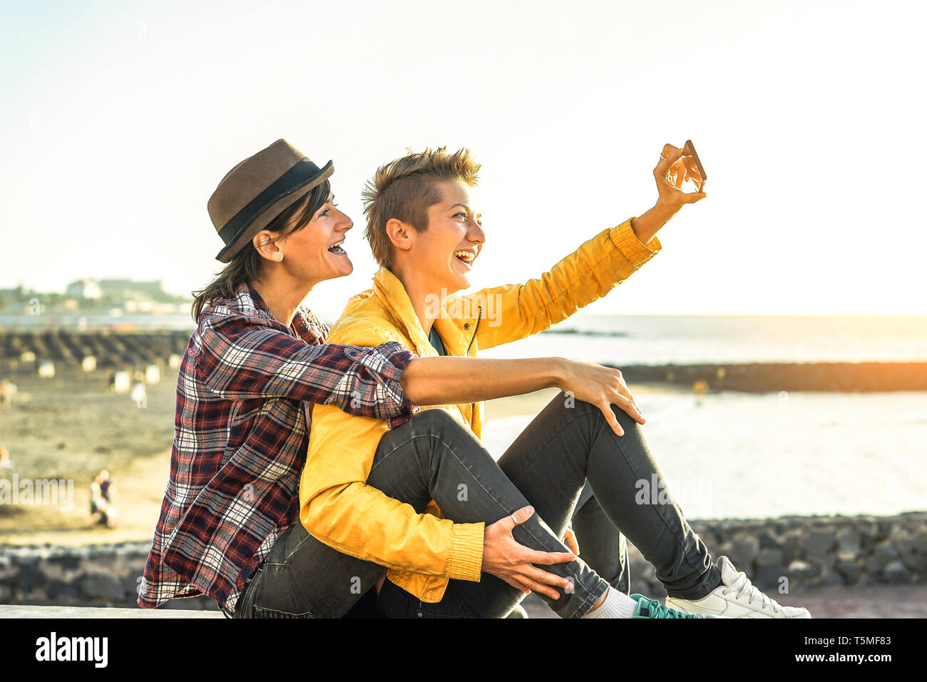 Happy Gay Couple Taking A Selfie With Mobile Smart Phone Camera On The Beach At Sunset Lesbians Having Fun In Holiday Stock Photo Alamy