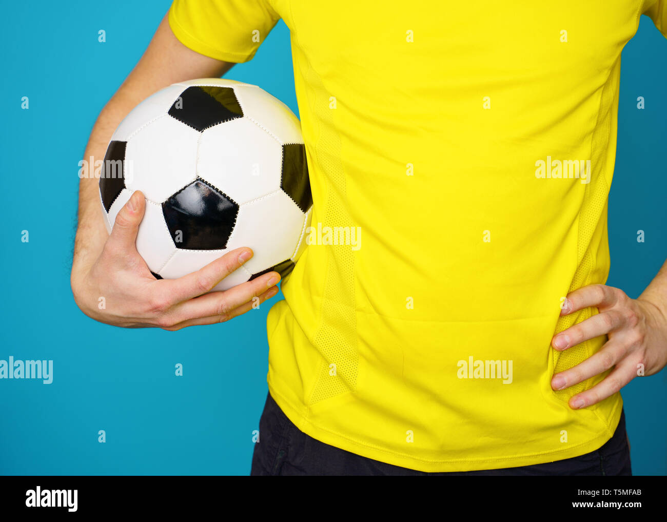 Man is socccer fan in yellow t-shirt with soccer ball Stock Photo