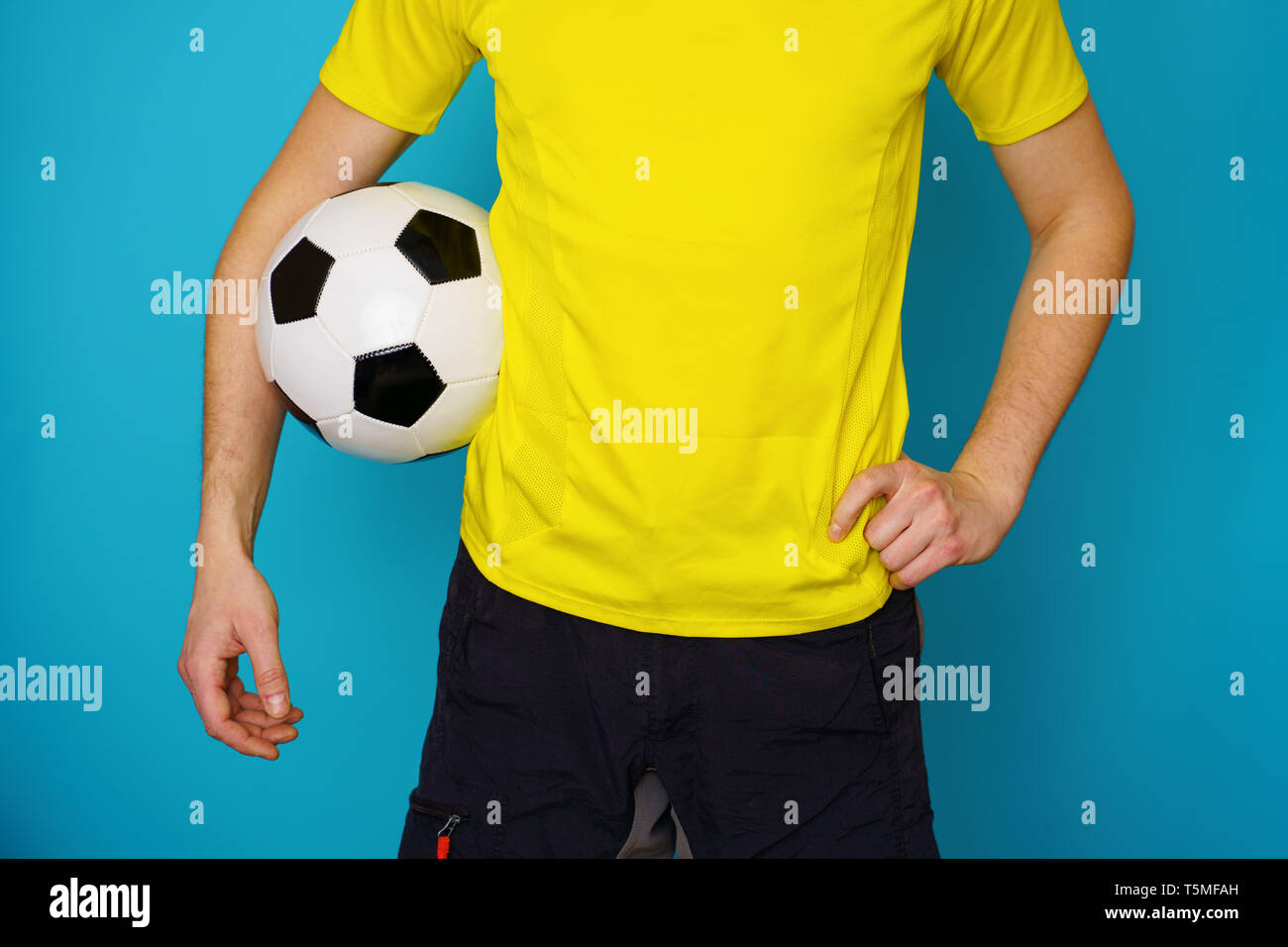 Man is socccer fan in yellow t-shirt with soccer ball Stock Photo