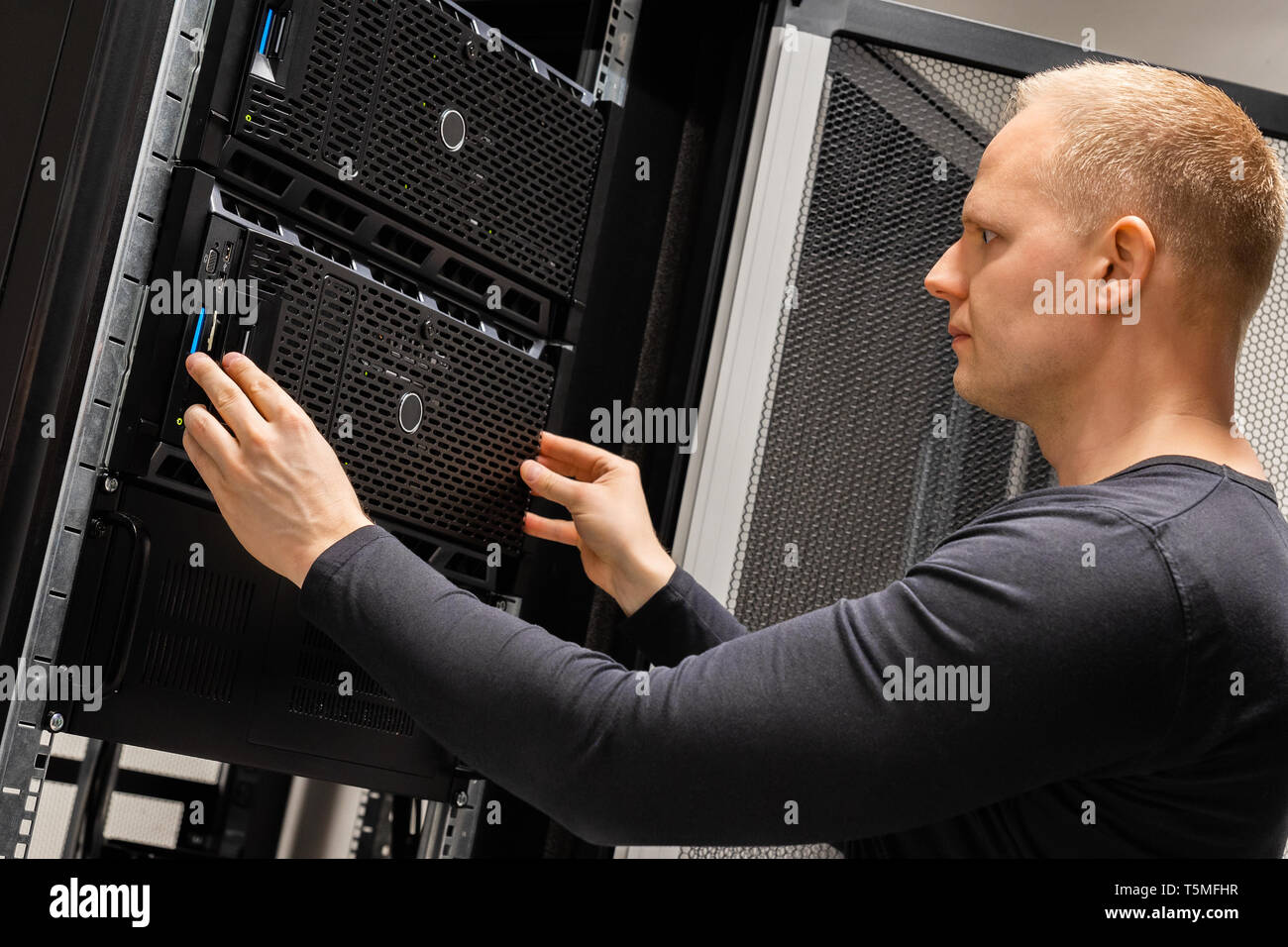 Male Technician Installing Servers In Enterprise Datacenter for Cloud Hosting Stock Photo