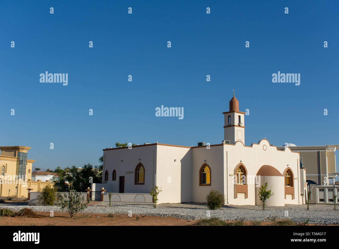 White Mosque in a residential area in the Middle East with a blue sky in the late afternoon sunshine. Stock Photo