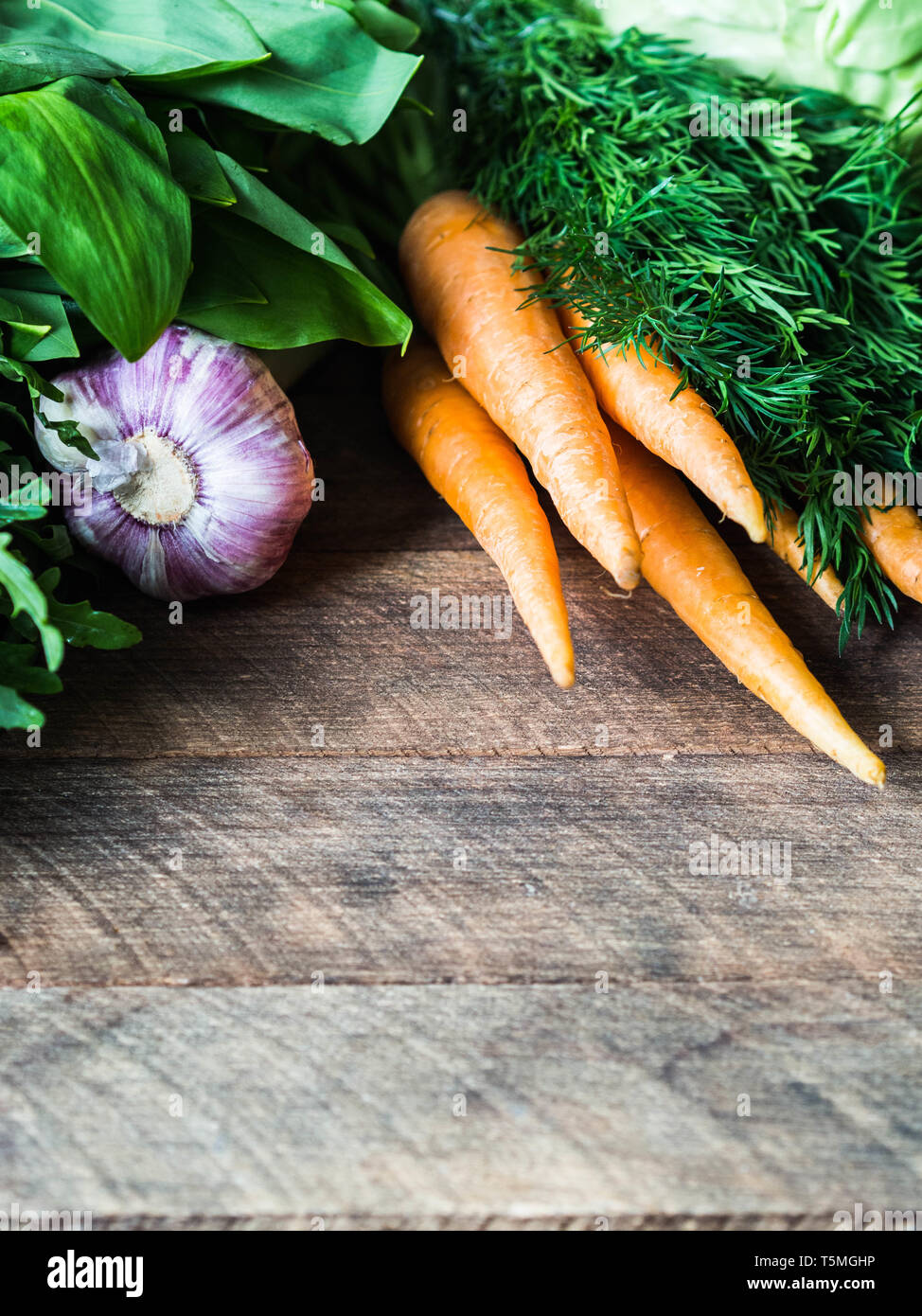 Fresh Spring vegetables and herbs frame on wood rustic background. Spring harvest of fresh vegetables. Stock Photo