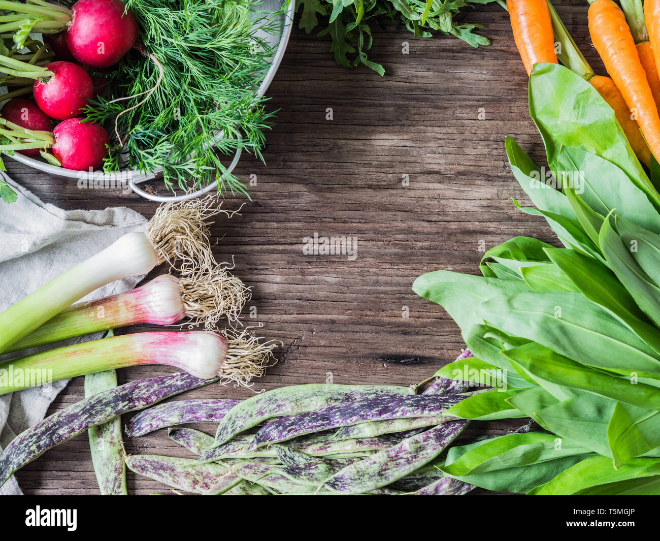 Fresh Spring vegetables and herbs frame on rustic wood background. Spring harvest of fresh vegetables. top view Stock Photo