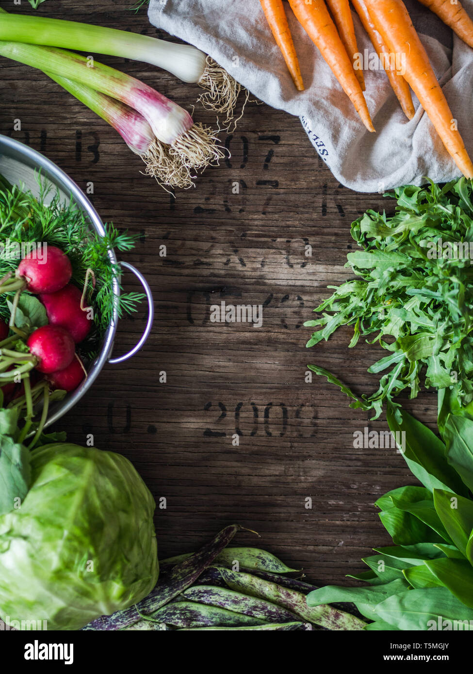 Fresh Spring vegetables and herbs frame on rustic wood background. Spring harvest of fresh vegetables. top view Stock Photo