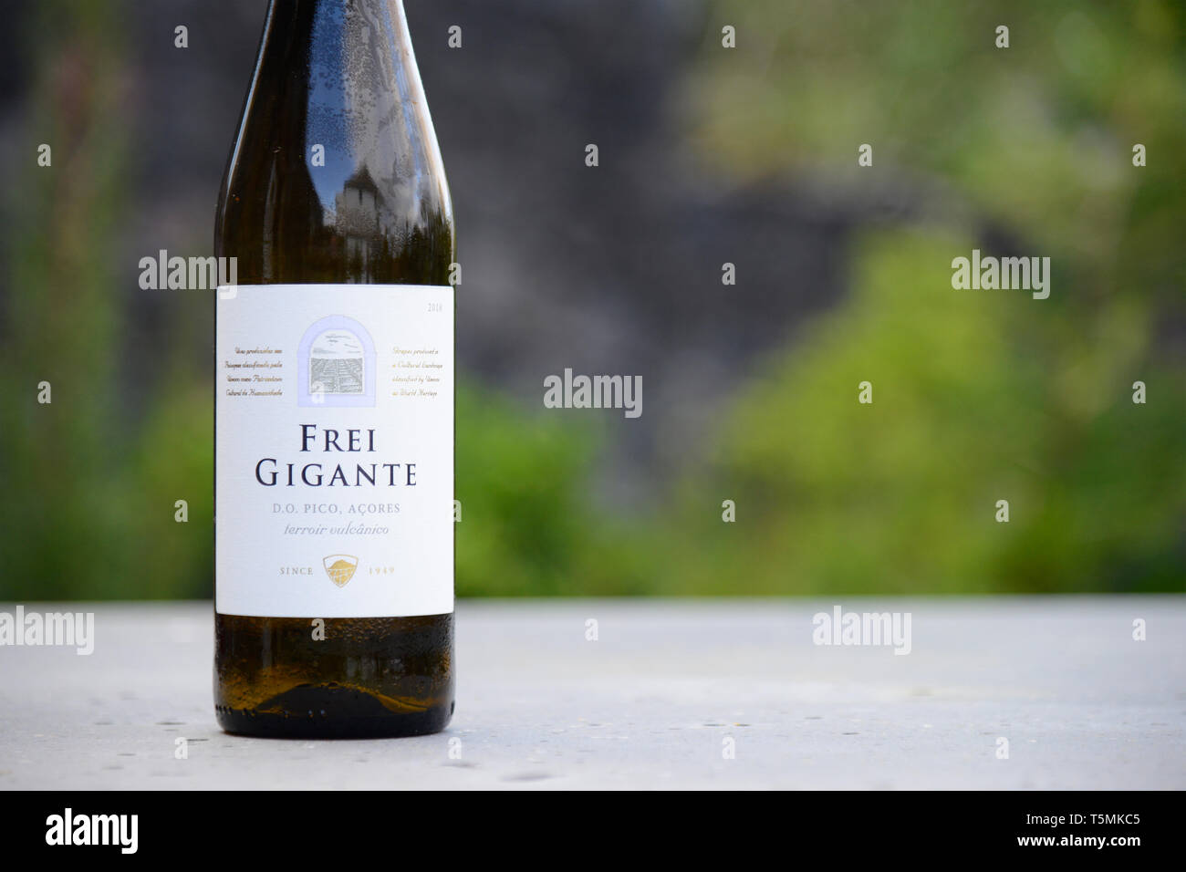 AZORES, PORTUGAL - APRIL 19, 2019: A bottle of white Frei Gigante wine sits on a table  in Pico Island, Azores. A typical wine from Pico Island in Azo Stock Photo