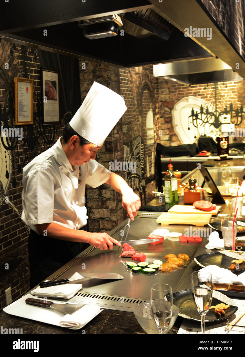 A Japanese Teppanyaki chef grilling Kobe beef steaks in a traditional restaurant in Kobe, Japan. Stock Photo