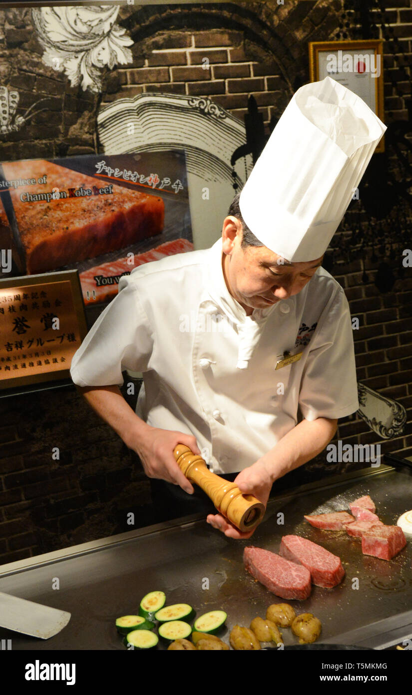 A Japanese Teppanyaki chef grilling Kobe beef steaks in a traditional restaurant in Kobe, Japan. Stock Photo
