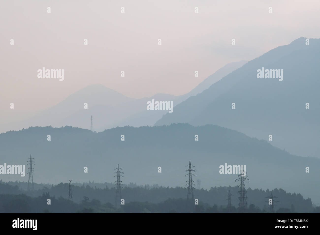 In Japan, the morning and a scenic beautiful view of mountains against the sunlight, electrical pylon and fog. Stock Photo