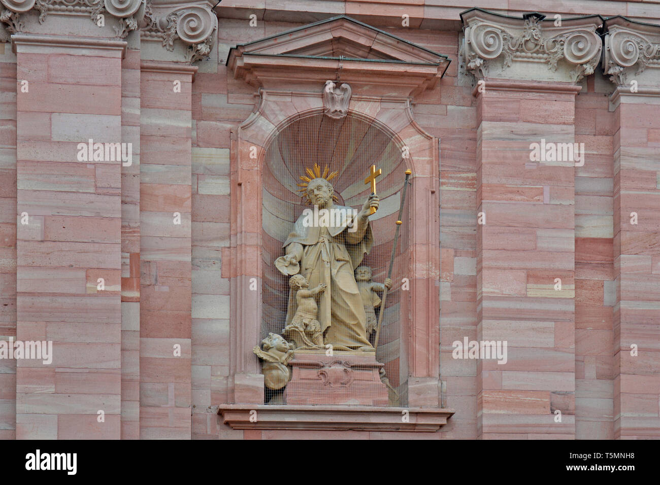 Statue of Saint Franz Xaver, holding a golden cross and baptizing a small boy and a second boy holds his staff at Jesuitenkirche church Stock Photo