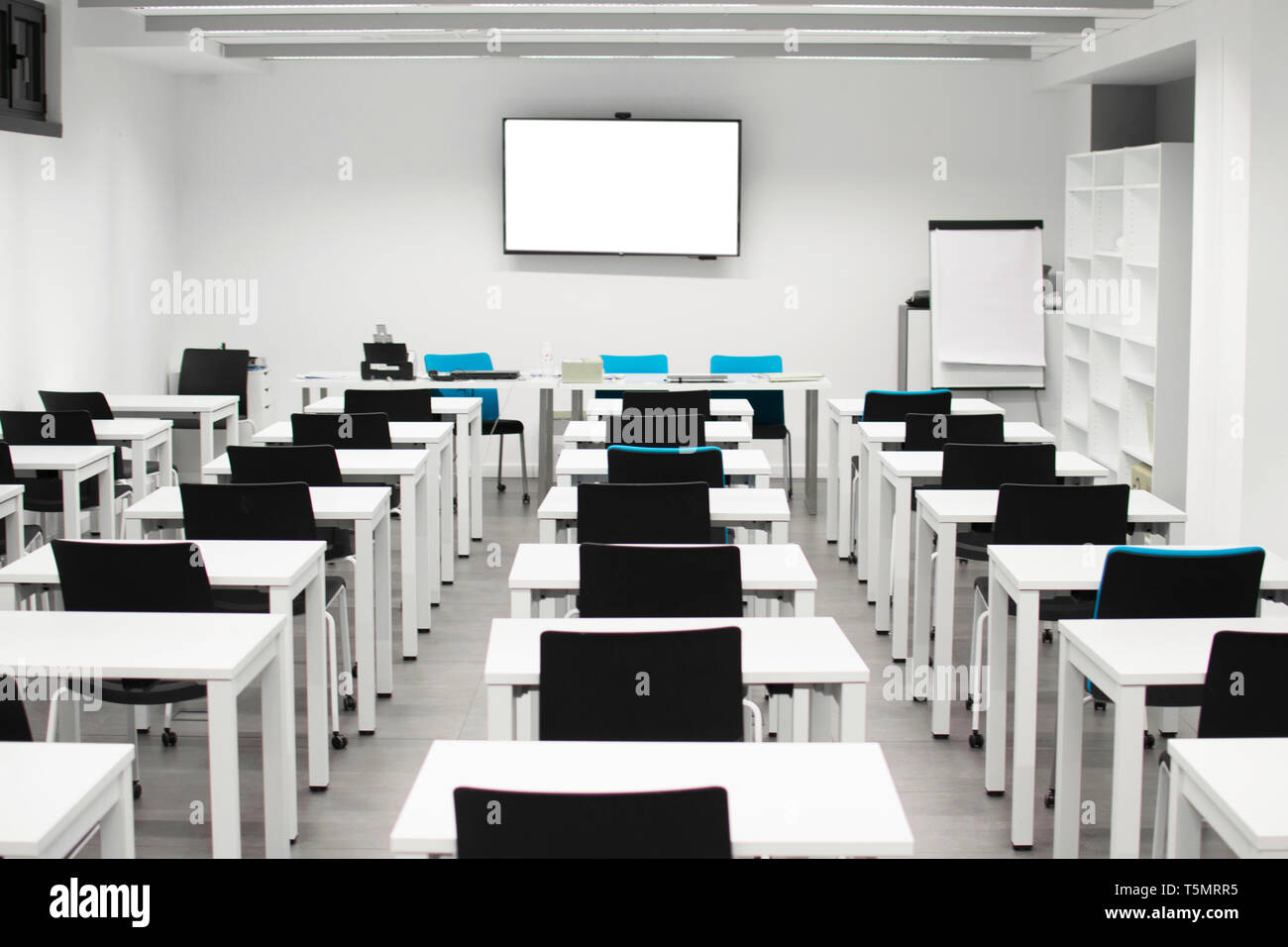 Classroom empty. High school or university desk or table and chairs in a row. Exam test room. Projecting digital blackboard Stock Photo