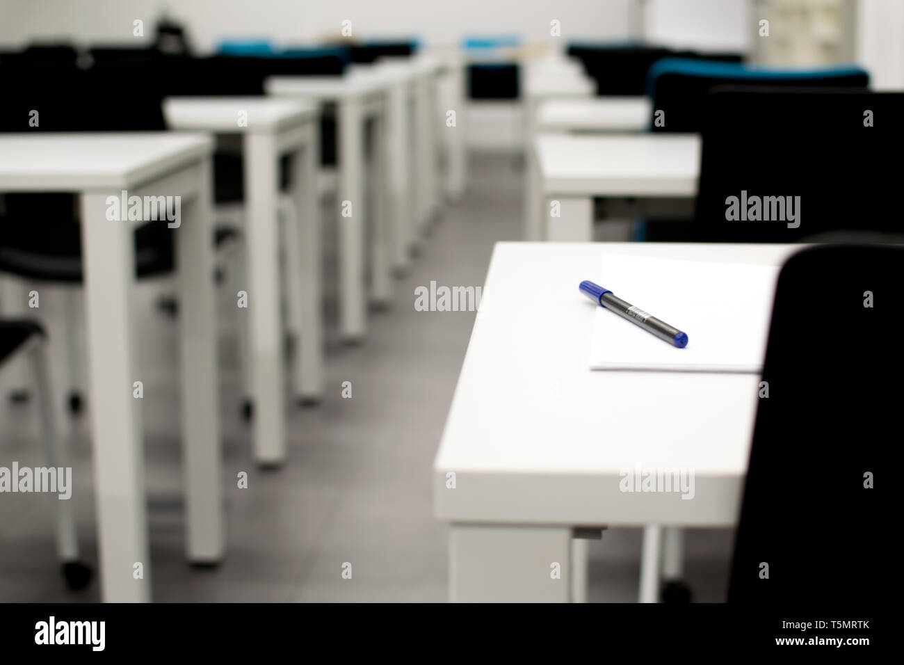 Classroom empty. High school or university desk or table with a pen on top. Exam test room Stock Photo