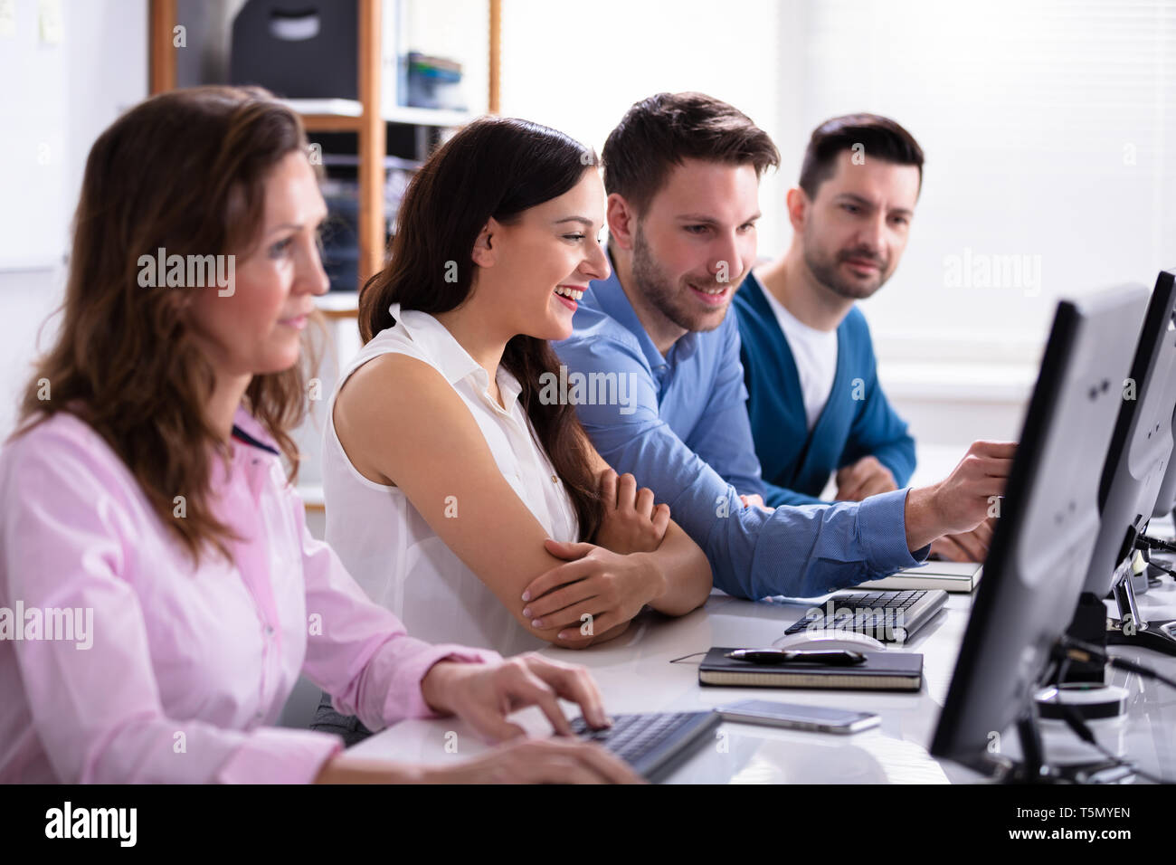 Businessman Pointing On Computer Screen While Talking With Her Colleague Stock Photo