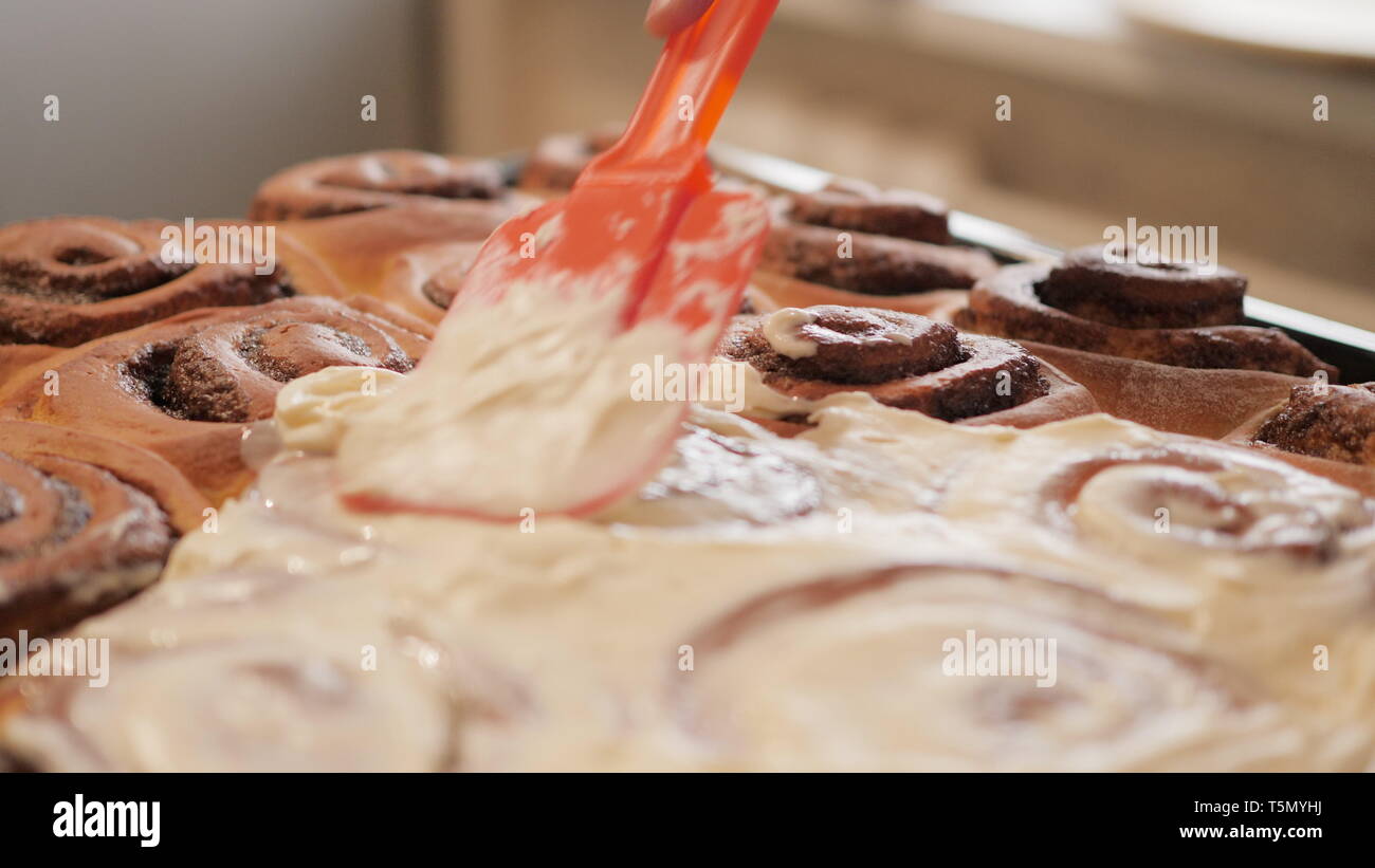 woman or man hand spreading a white butter cream on fresh hot cinnamon buns  with a special spatula in slow motion 4K video Stock Photo - Alamy