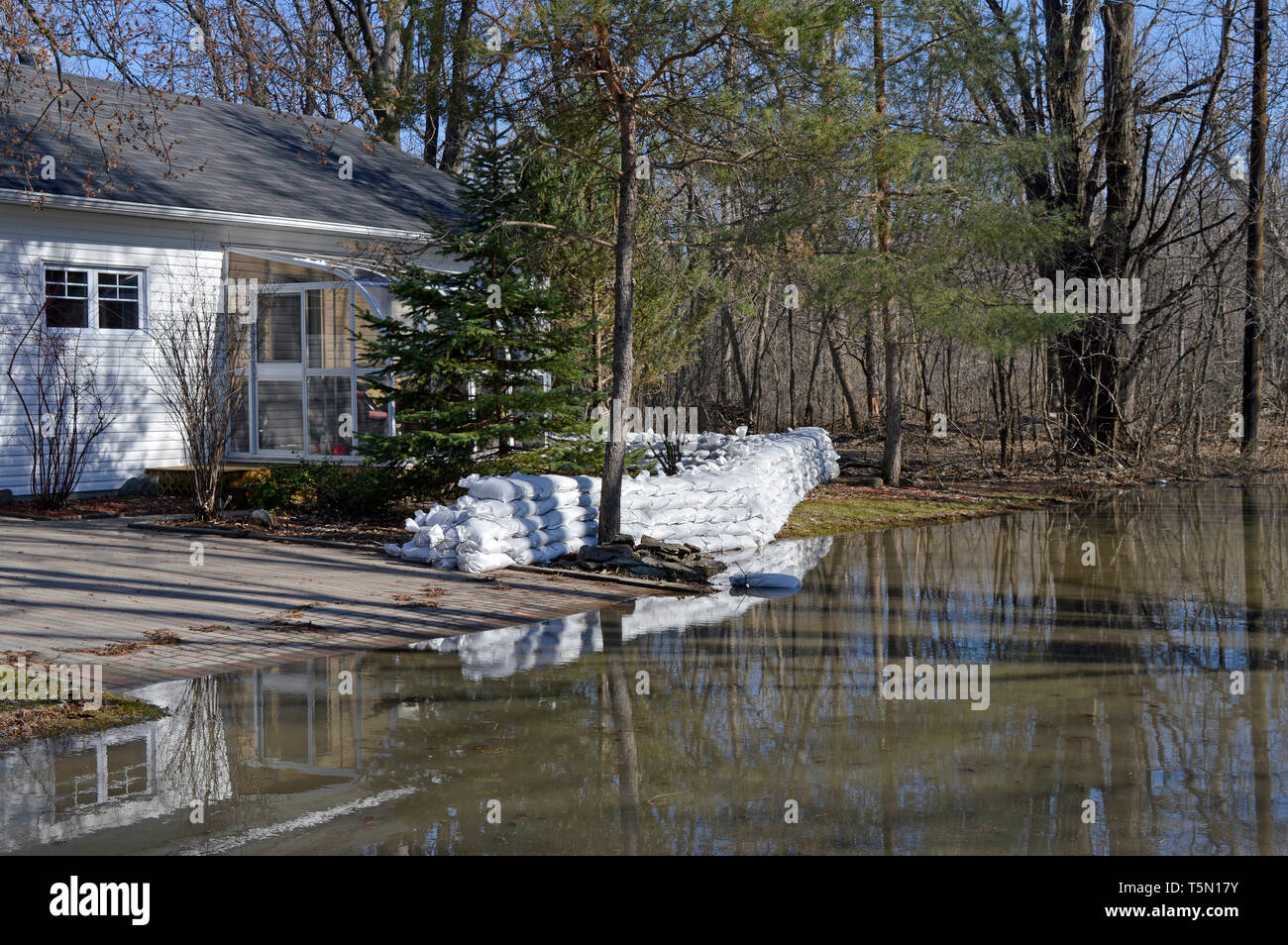 A wall of sand bags protects a lonely home in a forest in Gatineau, Quebec Stock Photo