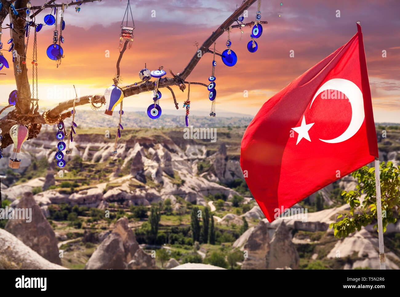 Evil eyes, balloon and Turkish flag on the tree in Goreme panorama at sunset sky Cappadocia, Turkey Stock Photo